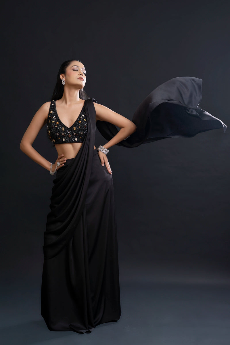 Woman in a black saree with a draped fabric against a dark background