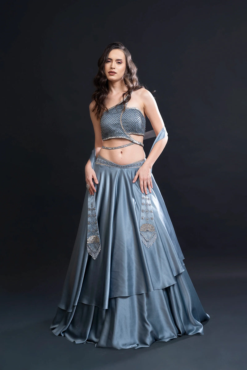 Woman wearing a blue traditional outfit with intricate designs on a black background