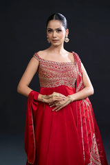 Woman in a red traditional outfit with intricate patterns on a black background