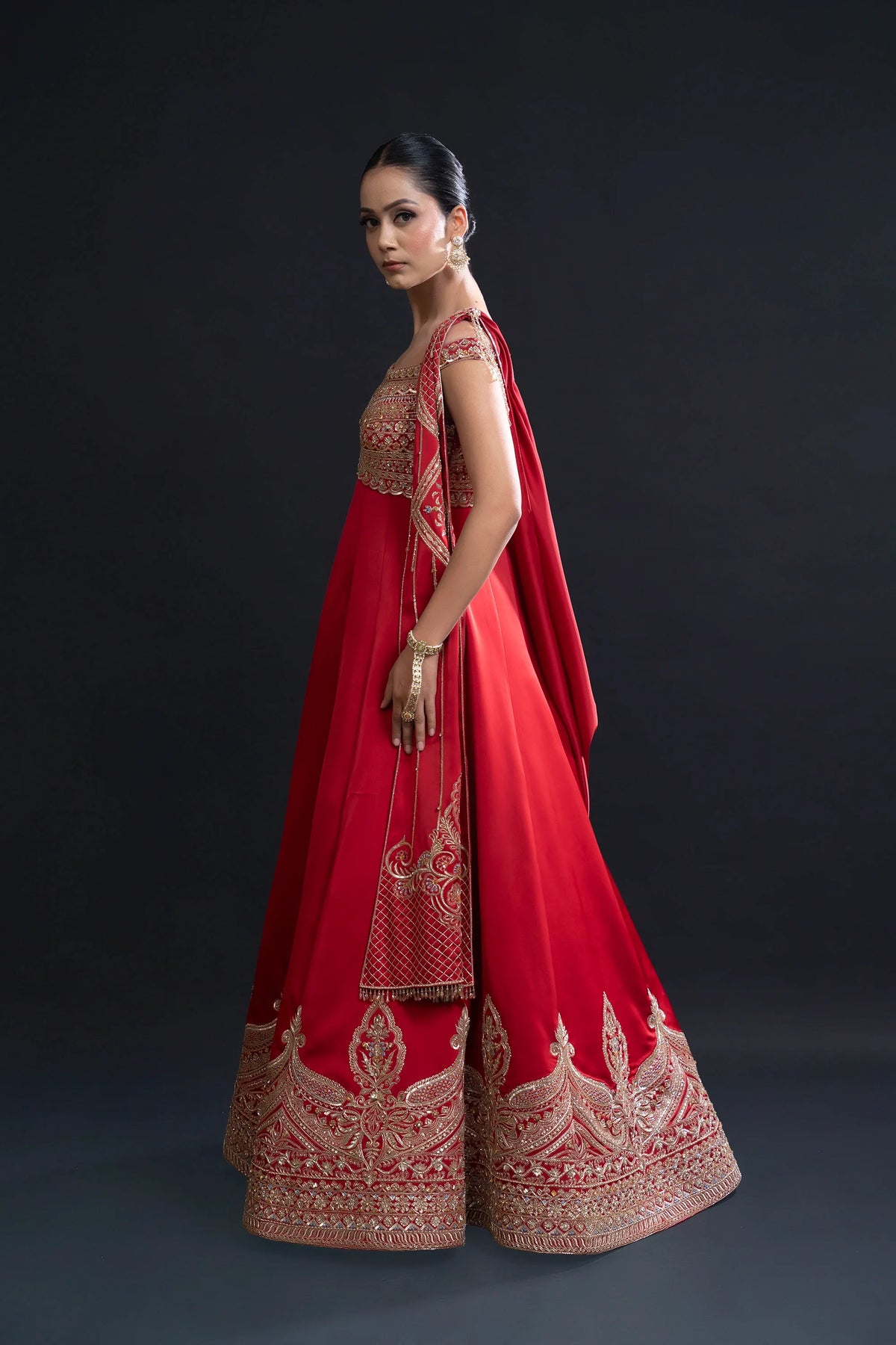 Woman wearing a red traditional outfit with intricate patterns on a dark background