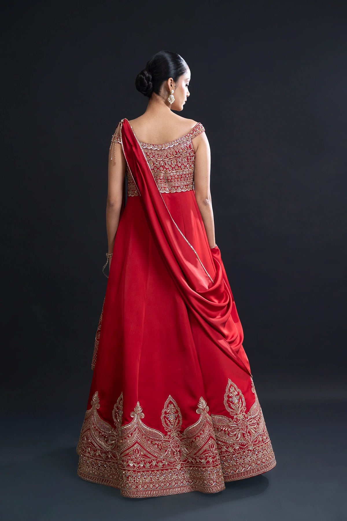 Red saree with gold embroidery on a dark background