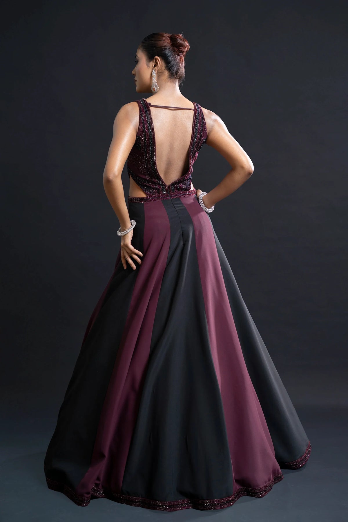 Woman wearing a two-tone dress with open back on a dark background