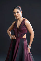 Woman wearing a burgundy evening gown with cut-out design on a dark background