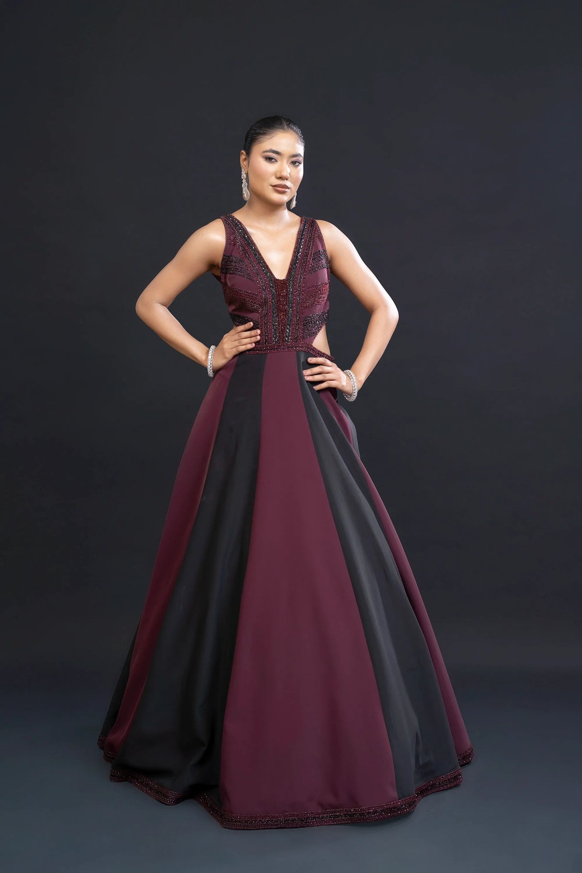 Woman wearing a burgundy and black evening gown against a dark background