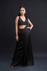 Woman wearing a black saree with a black blouse against a dark background
