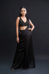 Woman wearing a black saree with a matching blouse against a dark background