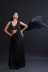 Woman in a black saree with a draped fabric against a dark background