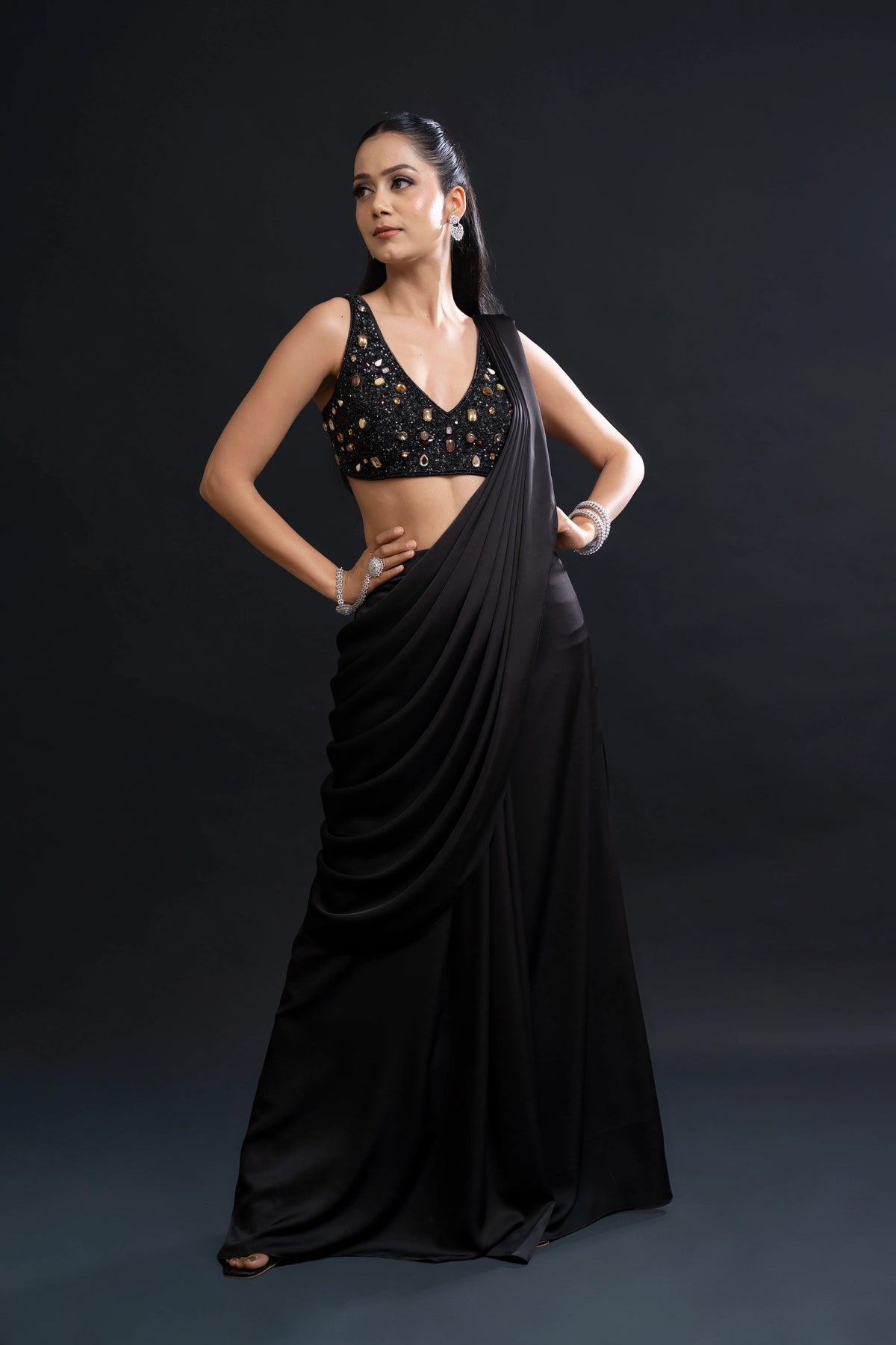 Woman wearing a black saree with a gold blouse against a dark background