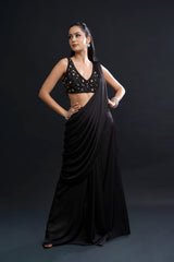 Woman wearing a black saree with a gold blouse against a dark background