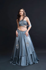 Woman wearing a blue traditional outfit with intricate designs on a black background