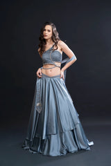 Woman wearing a gray outfit with a long skirt and top on a black background