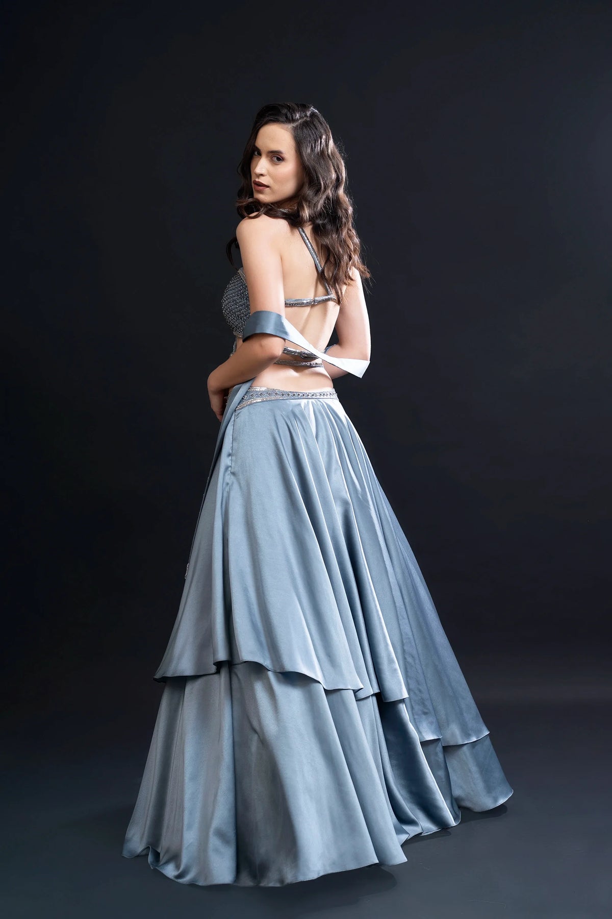 Woman wearing a light blue layered skirt and top against a dark background