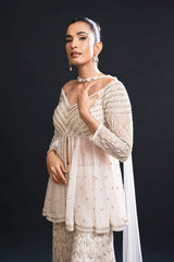 Woman wearing a white embroidered outfit against a black background